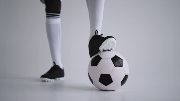 μπάλα ποδοσφαίρου και πόδια του ποδοσφαίρου σε μπότες και κάλτσες γόνατο στο στούντιο, closeup view - Πλάνα, βίντεο