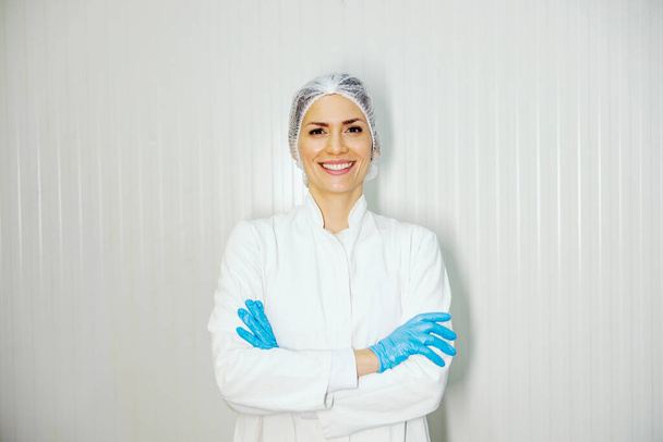 Portrait of a female factory worker with arms crossed smiling at the camera. - Foto, Bild