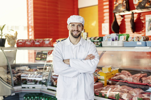Portrait of a proud smiling butcher at butcher shop. - Photo, Image