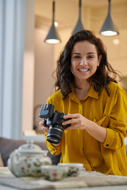 Young female photographer in a mustard shirt with camera in hands - Photo, Image