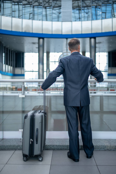Man standing near suitcase with back to camera - Zdjęcie, obraz