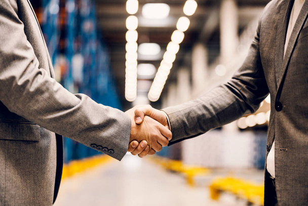 Close up of a business partners shaking hands at warehouse. - 写真・画像