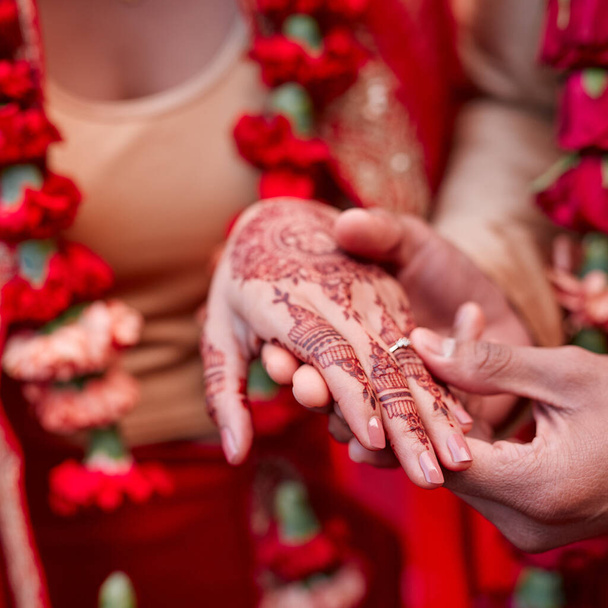 Ten pierścionek to znak mojej miłości. Przycięte zdjęcie hinduskiej pary wymieniającej obrączki w dniu ślubu. - Zdjęcie, obraz