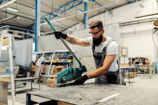 A worker using manual metal cutter for cutting metal parts. - Fotografie, Obrázek