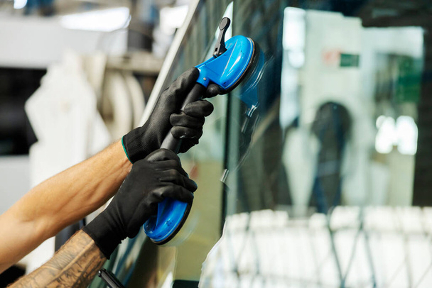 Nahaufnahme von Hand beim Glasaufsetzen im Mechaniker-Geschäft. - Foto, Bild