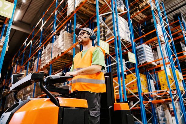 A worker with voice picking headset driving orders for shipping on forklift at storage. - Fotoğraf, Görsel