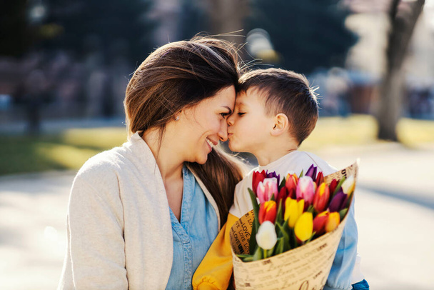 A son kissing mother and giving her tulips for mother's day. - Zdjęcie, obraz