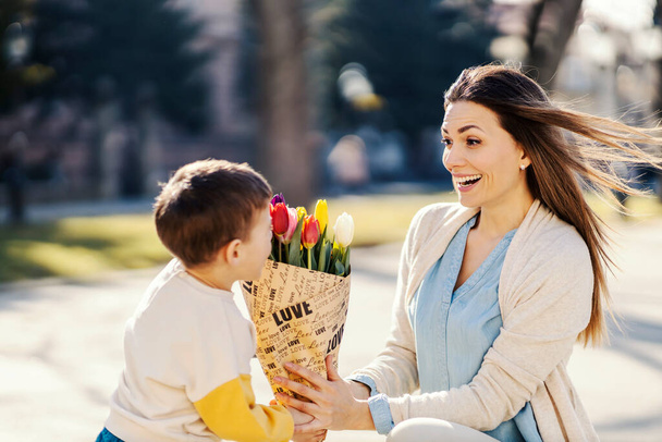 Здивована жінка, що приймає тюльпани, формує сина в день матері
. - Фото, зображення
