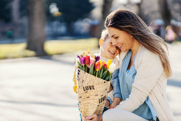 Щаслива мати тримає тюльпани, які вона отримала від свого сина в день матері
. - Фото, зображення