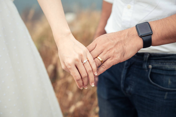 Zblízka nevěsta a ženich stojí v lese a drží se za ruce se snubním prstenem v předsvatební den. Svatební šaty, Ženatý pár - Fotografie, Obrázek