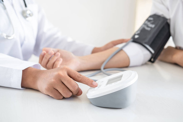 Orvos segítségével mérési vérnyomás ellenőrzése beteg vizsgálatával, bemutató eredmények tünete és ajánljuk kezelési módszer, egészségügyi és orvosi koncepció. - Fotó, kép