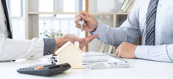 Estate agent giving house keys to client after signing agreement contract real estate with approved mortgage application form, concerning mortgage loan offer for and house insurance. - 写真・画像