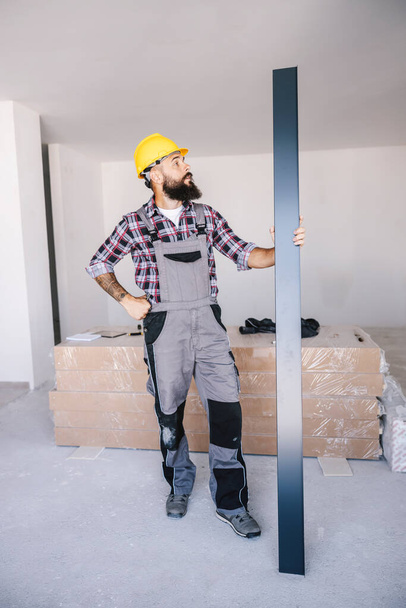Un bricoleur tenant une barre métallique comme matériau de construction sur son lieu de travail. - Photo, image