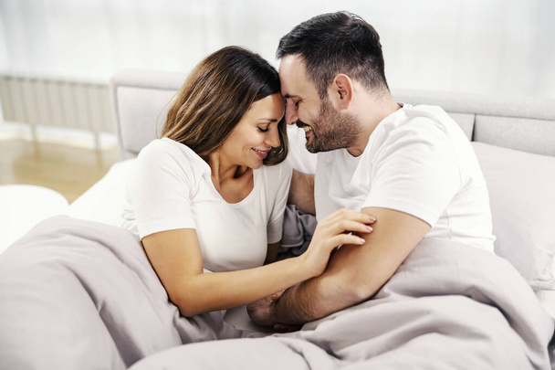 Счастливая утренняя пара с романтическими моментами в постели в их уютном доме. - Фото, изображение