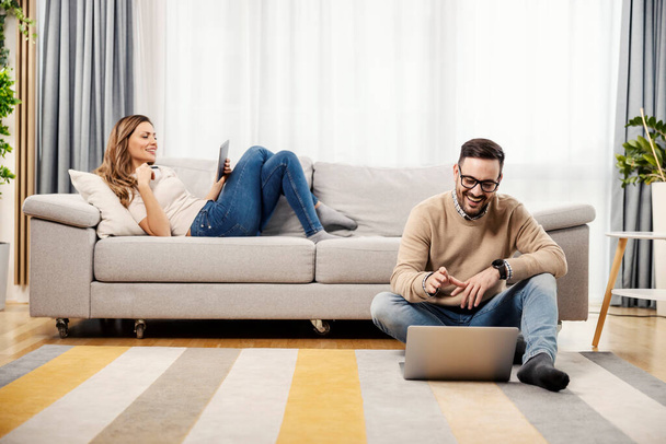 Um casal feliz em sua casa acolhedora usando tecnologias. - Foto, Imagem