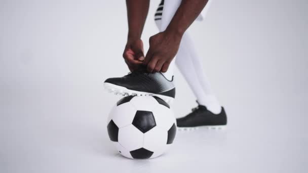 piłkarz jest zaciskanie sznurowadła buty piłkarskie stojące nogi na piłkę, szczegóły w photostudio - Materiał filmowy, wideo
