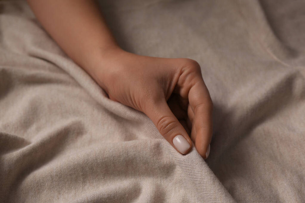 Woman touching soft beige fabric, closeup view - 写真・画像