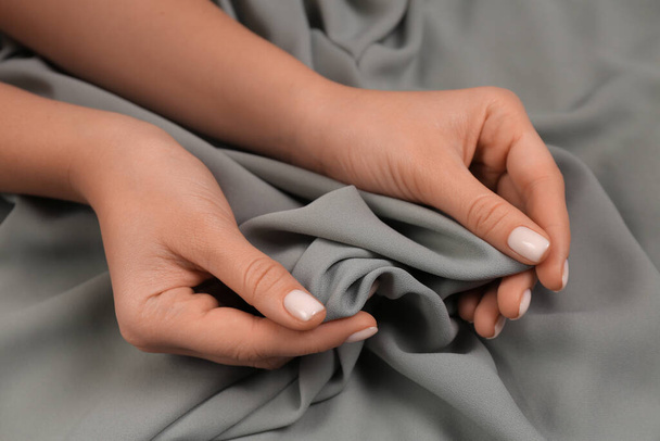 Woman touching smooth grey fabric, closeup view - Fotó, kép