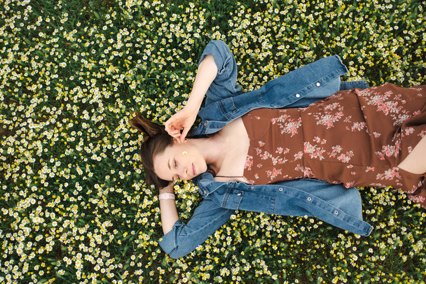 Щаслива жінка лежить в зеленому ромашковому полі
 - Фото, зображення