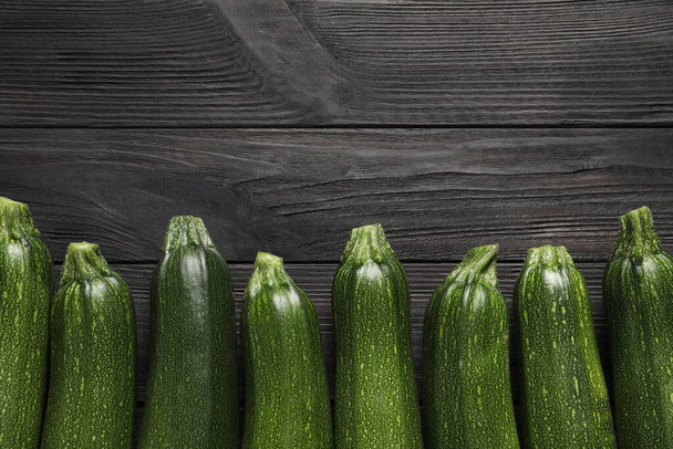 Zucchinis maduros crudos sobre mesa de madera negra, tendido plano. Espacio para texto - Foto, Imagen