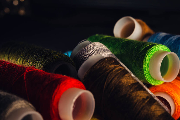 multi-colored spools of thread on a black background - Фото, зображення