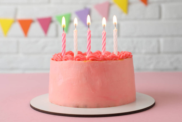 Cute bento cake with tasty cream and burning candles on pink table - Foto, imagen
