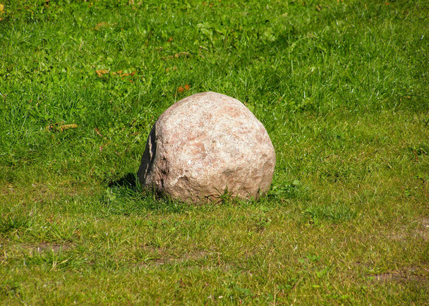 Stein auf dem Rasen mitten im grünen Gras - Foto, Bild