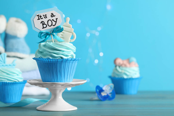Beautifully decorated baby shower cupcake with cream and boy topper on light blue wooden table. Space for text - Photo, Image