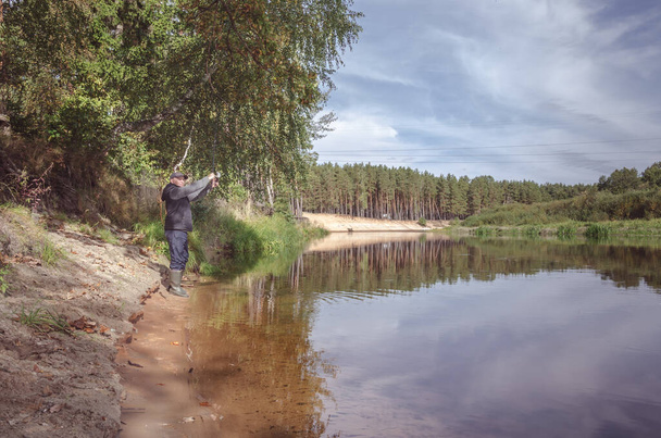 Fisherman on the bank of a beautiful river on a sunny day. - Φωτογραφία, εικόνα