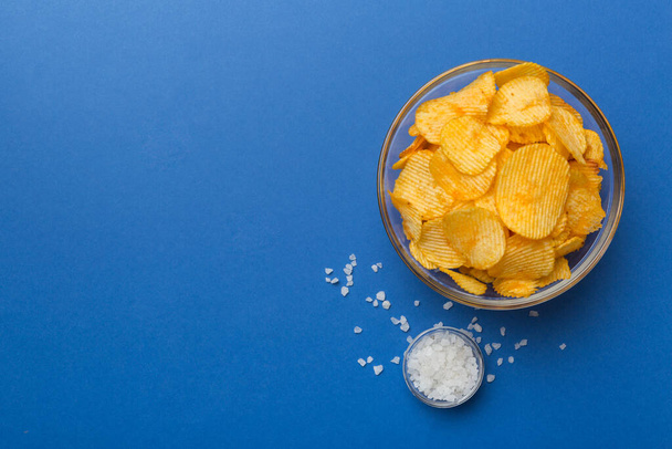 chipsy ziemniaczane z solą na kolorowym tle widok z góry z miejsca kopiowania. - Zdjęcie, obraz