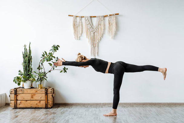 Virabhadrasana is the 3rd pose of the won in yoga. The girl performs the asana standing on one leg of the arm pulls forward the other leg stretched back. High quality photo - Φωτογραφία, εικόνα