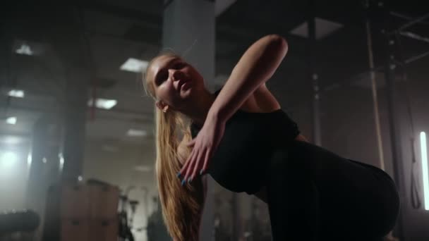 фитнес-тренировки в тренажерном зале, молодая спортсменка согревает тело перед тяжелыми упражнениями на спортивном оборудовании - Кадры, видео