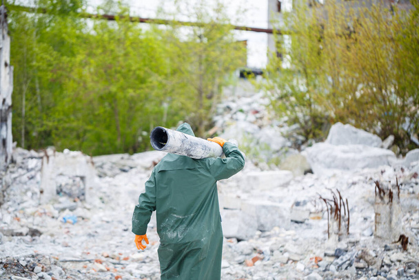 Een man met een beschermend masker en beschermende kleding verkent de gevarenzone. Ecologische catastrofe. selectieve focus - Foto, afbeelding
