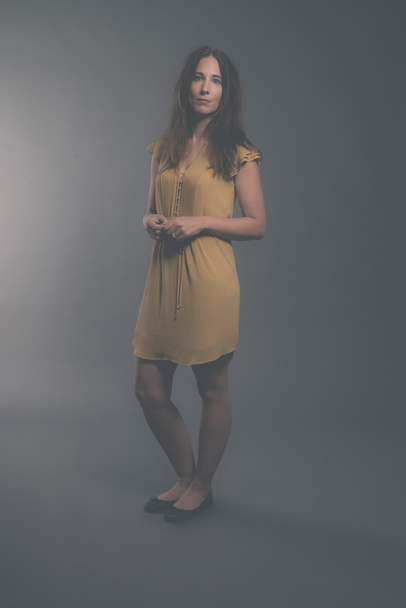 Shy brunette fashion woman wearing yellow dress. Studio shot aga - Foto, Imagem