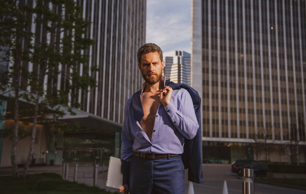 Caucasian business man in suit comes out office. concept of end working day. Sexy fashion businessman, open shirt. - 写真・画像