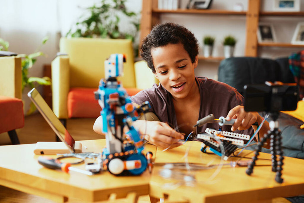 Egy tanult kisfiú, aki videóra veszi magát, és robotot csinál. Elektronikai és mesterséges intelligencia oktatás. - Fotó, kép