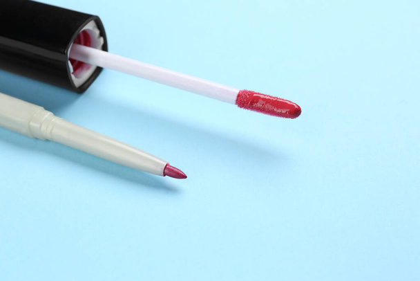 Lip pencil and brush of liquid lipstick on light blue background, closeup. Cosmetic product - Photo, Image
