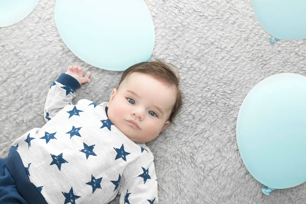 piękny chłopiec cztery miesiące stary leżący na łóżku z niebieskimi balonami - Zdjęcie, obraz