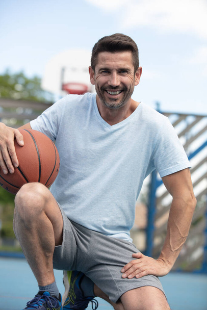 portrait of middle-aged man crouched holding a basketball - Foto, Imagem