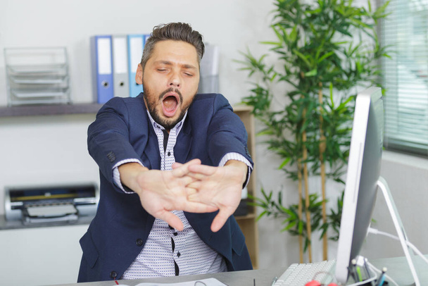 yawning tired business man sitting at workplace in office - Φωτογραφία, εικόνα
