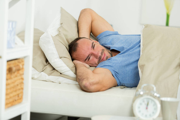 портрет людини, що розтягується і посміхається, лежачи в ліжку
 - Фото, зображення