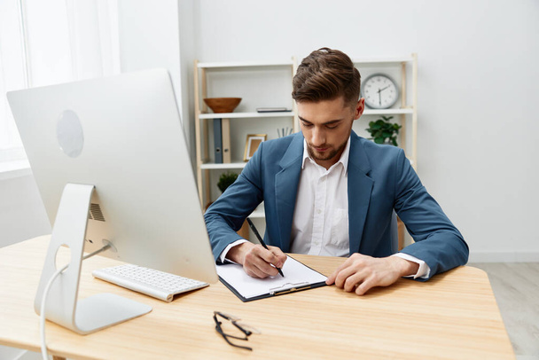 hombre de negocios guapo escribe en documentos en el escritorio en el ejecutivo de la oficina - Foto, imagen