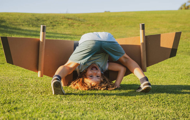 Funny child upside down on grass. Childhood imagination, kid dream to adventure travel. Travel and vacation with children. Kids freedom and carefree concept - Fotoğraf, Görsel