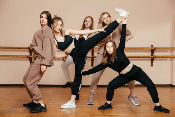 Modern dancers pose against the background of a dance studio, performing elements of modern dance, a professional group of dancers is preparing for a concert - Фото, изображение