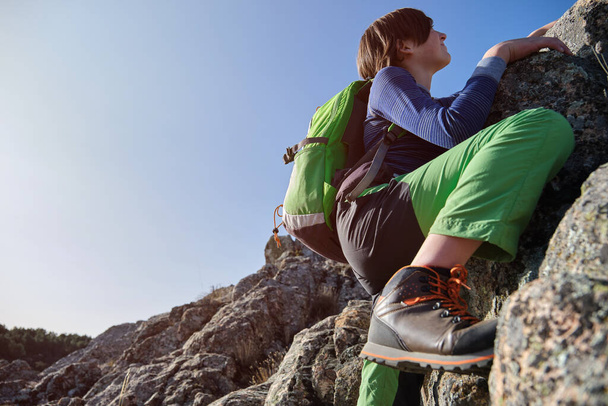 Adolescente con mochila trepando rocas en las montañas. - Foto, imagen