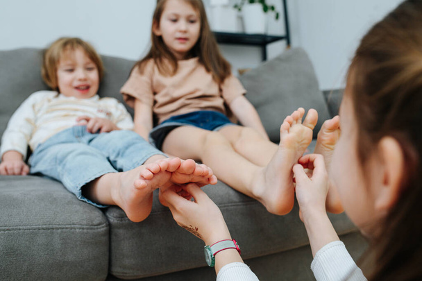 Blurred image of a girl conducting tickling competition between siblings. Focus on hands. - Photo, image