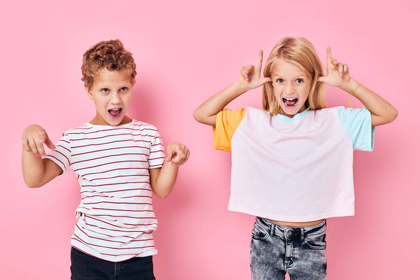 jongen en meisje leuk capriolen roze achtergrond - Foto, afbeelding