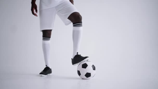 zwarte voetballer poseert met bal in studio met witte achtergrond, portret van voorwaarts - Video