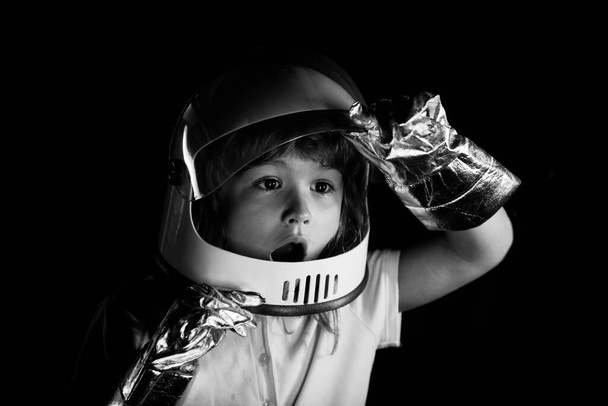 A little boy dreams of becoming an astronaut and flying into space. Cosmos childrens in spacesuit and helmet dreams. Close up excited kids face on neon color. - Foto, afbeelding