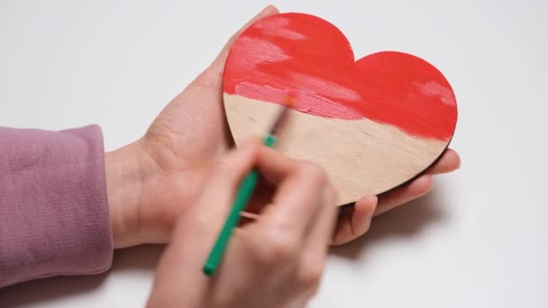 Hand paints a wooden heart in red. 4K resolution close up view video banner. DIY concept for Valentines Day, International Womens Day or mothers day - Footage, Video
